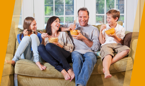 Family of four on couch eating dinner